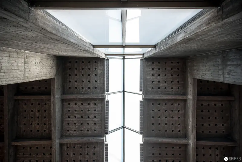 Geometric Concrete Interior with Perforated Panels and Central Skylight