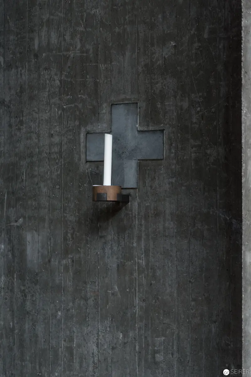Cross-Shaped Light Fixture on Dark Concrete Wall at Pfarre Oberbaumgarten