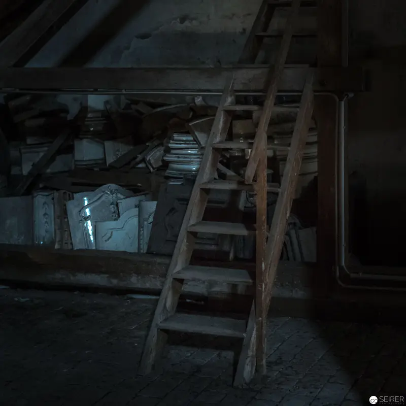 Wooden Ladder in Dimly Lit Attic Space with Vintage Storage Containers