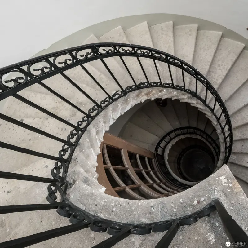 Spiraling Stone Staircase with Ornate Wrought-Iron Balustrade in Architectural Study