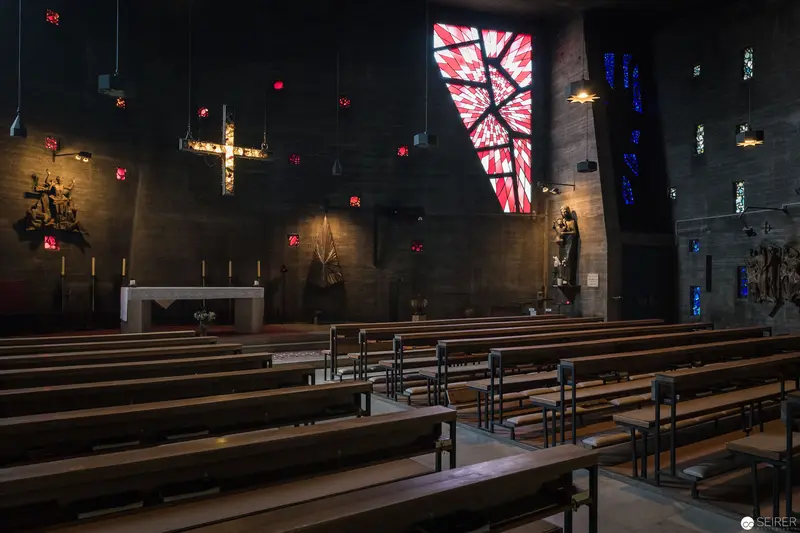 Interior of Pfarre zum guten Hirten with Illuminated Stained Glass and Liturgical Furnishings