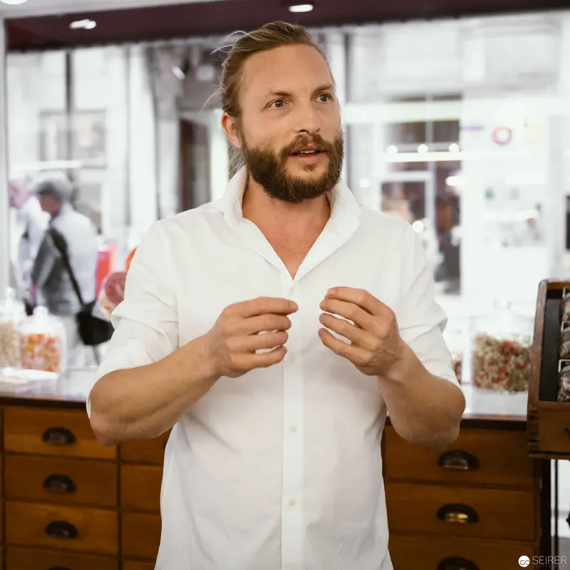 Zuckerlwerkstatt Owner in White Shirt Gesturing at Vienna Workshop
