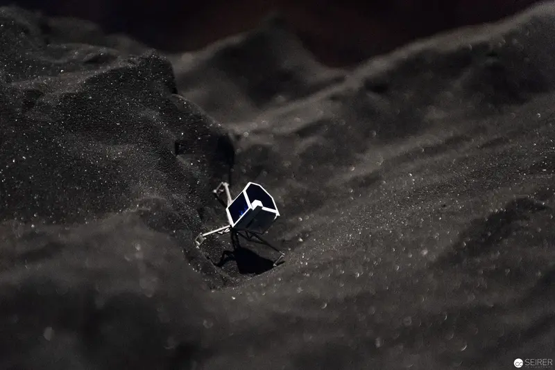 Miniature Spacecraft Nestled in Grainy Monochromatic Lunar-like Terrain