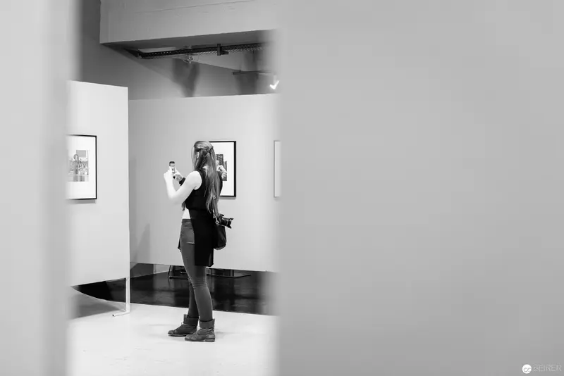 Gallery Visitor Observing Art Photograph in Minimalist White Exhibition Space