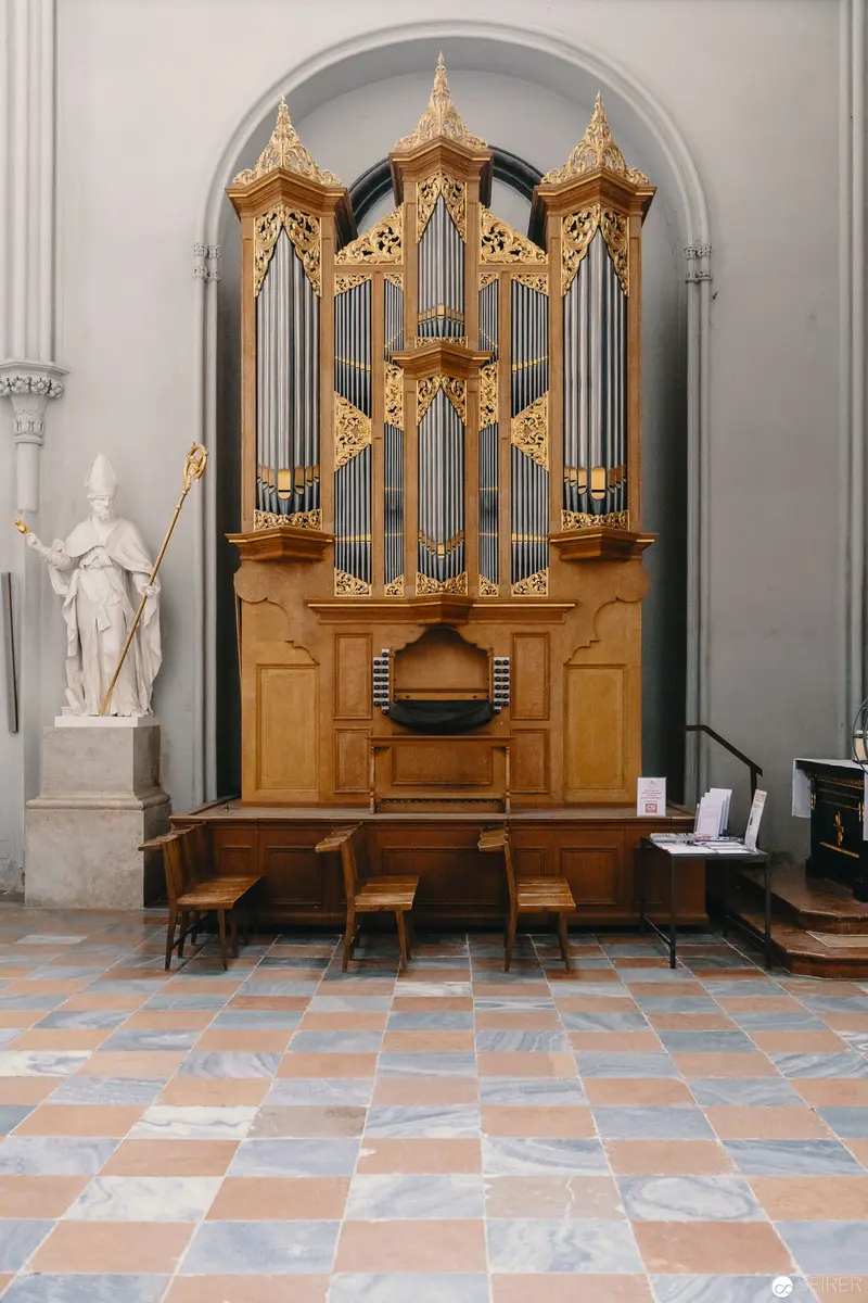 Baroque Pipe Organ in Ornate Interior with Checkered Floor and Marble Statue
