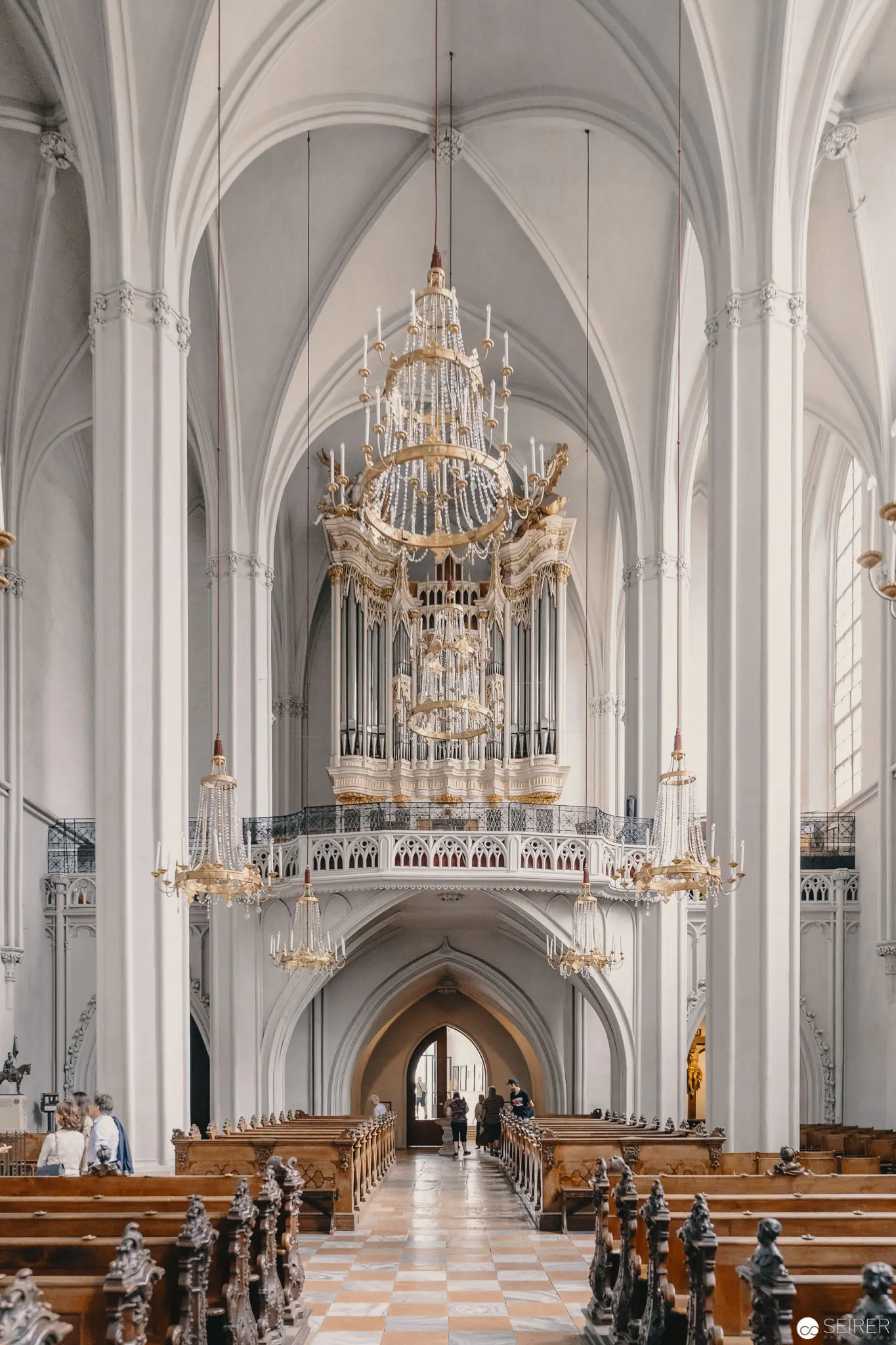 White Interior of Gothic Cathedral with Ornate Pipe Organ and Crystal Chandeliers
