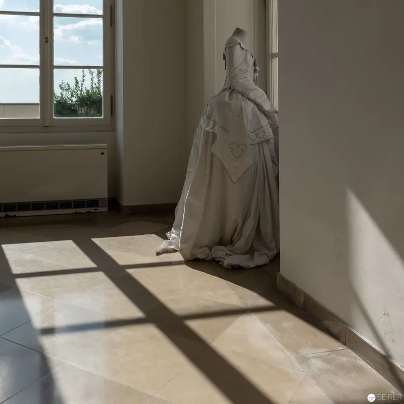 Sculptural Figure in White Dress Illuminated by Window Light