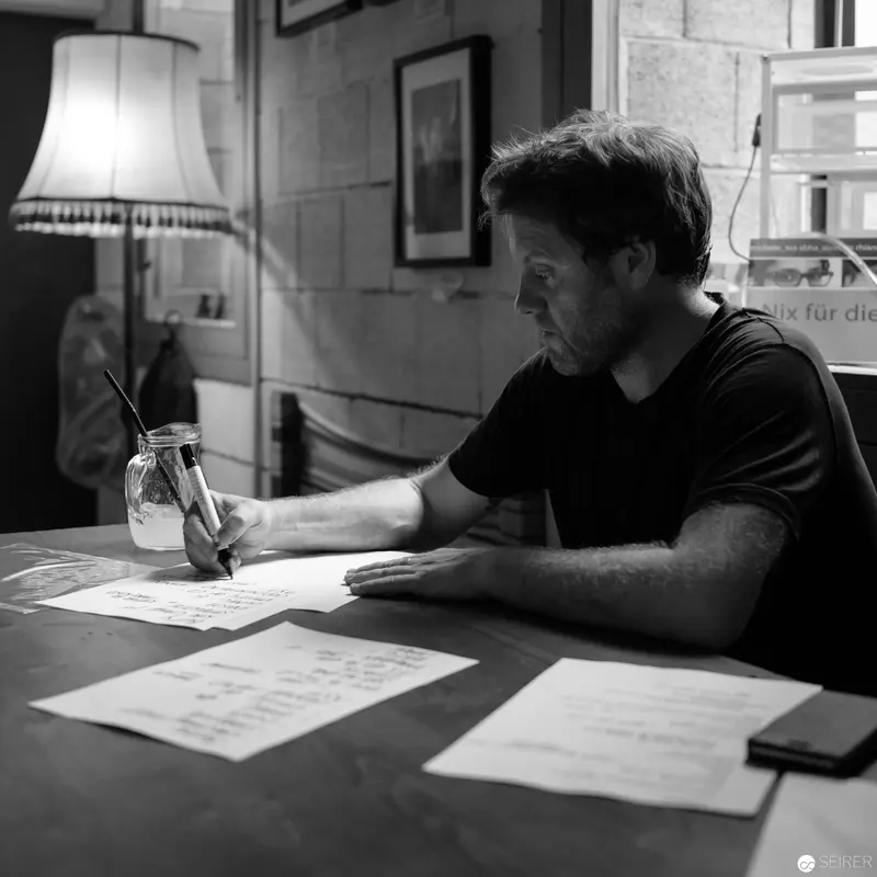 Contemplative Writer Working at Desk in Shadowy Monochrome Interior