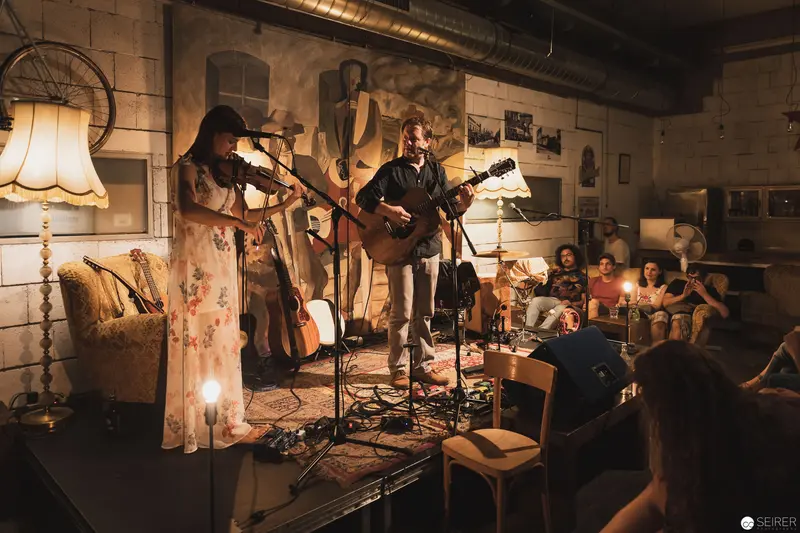 Intimate Acoustic Performance in Rustic Candlelit Interior with Attentive Audience