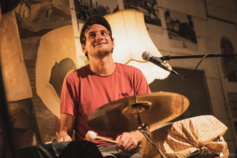 Energetic Drummer Performing in Intimate, Warmly Lit Music Venue
