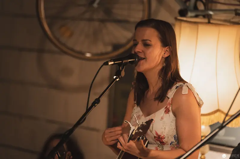 Intimate Acoustic Performance with Singer in Floral Top Near Bicycle Wheel