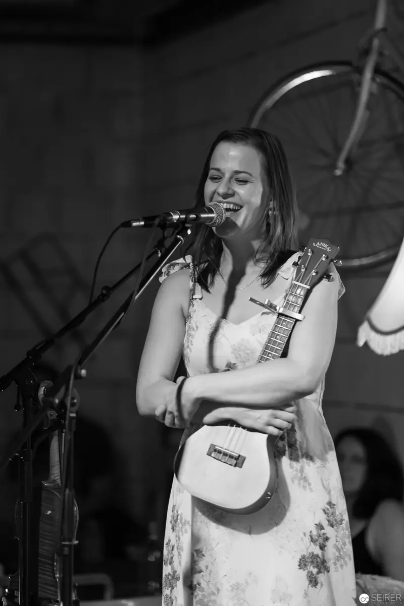 Musician Performing on Stage in White Floral Dress with Acoustic Guitar