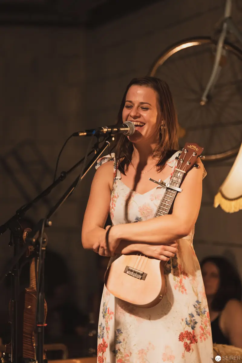 Musician Performing Intimate Concert in Soft Floral Dress with Acoustic Guitar