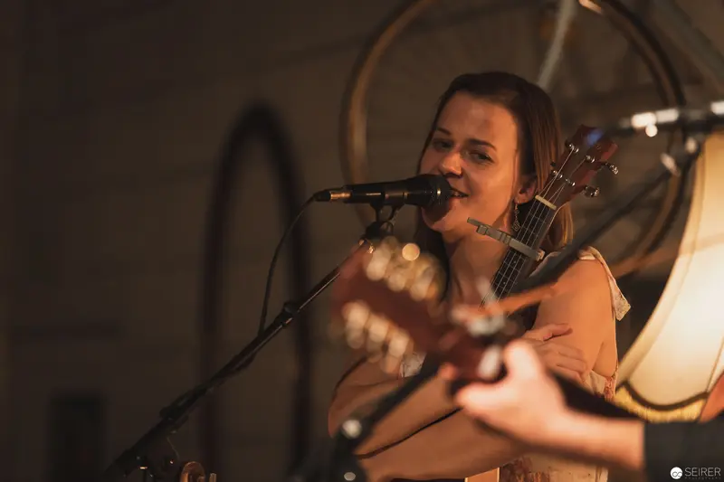 Singer Performing Intimate Acoustic Set with Guitar in Warm Stage Lighting