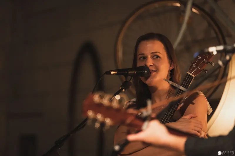 Intimate Acoustic Performance with Vocalist and Guitar in Warm Stage Lighting