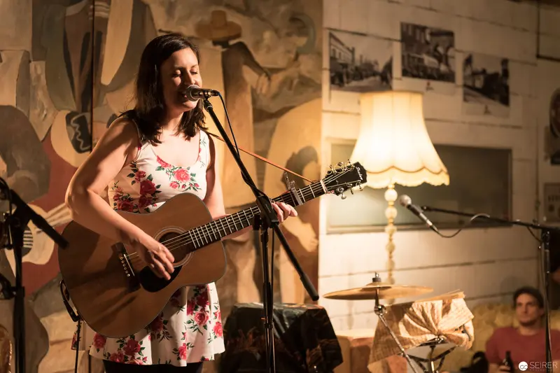 Acoustic Performance in Intimate Venue with Vintage Lamp and Mural Backdrop