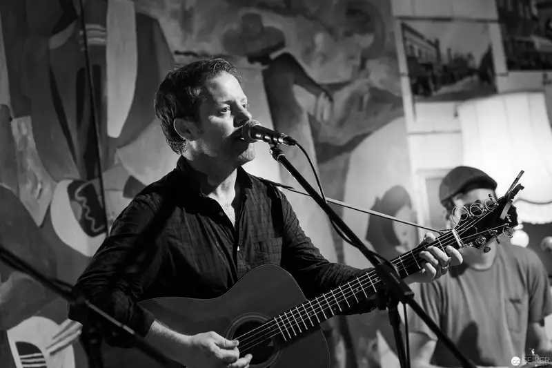 Acoustic Performer with Acoustic Guitar at Intimate Black and White Concert Venue