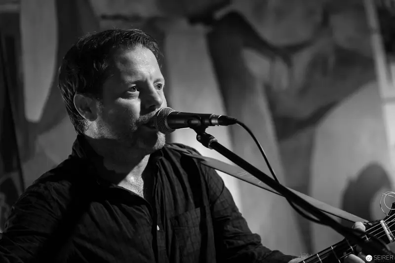 Passionate Performer Singing and Playing Guitar at Intimate Concert