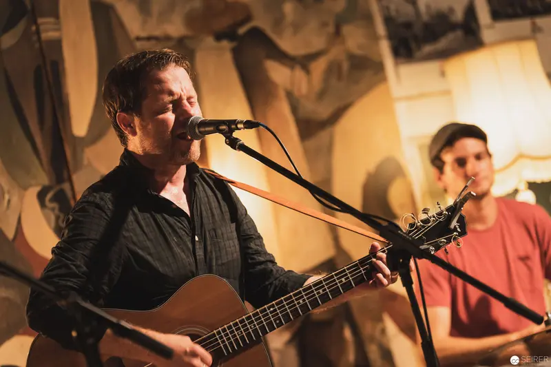 Acoustic Performance with Guitarist in Black Singing at Intimate Venue