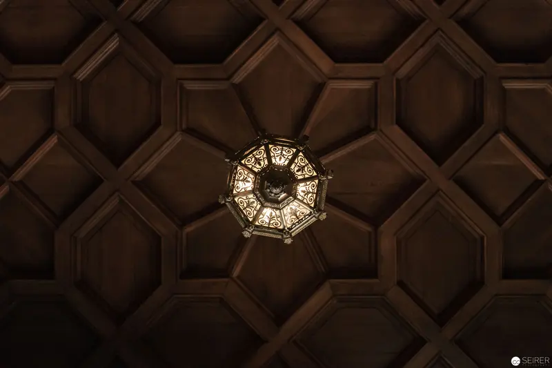 Ornate Ceiling Lantern Illuminating Geometric Hexagonal Wooden Paneling at Hermesvilla