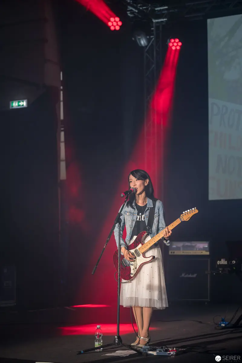 Haruka Performing at AniNite 2018 with Electric Guitar Under Dramatic Red Lighting