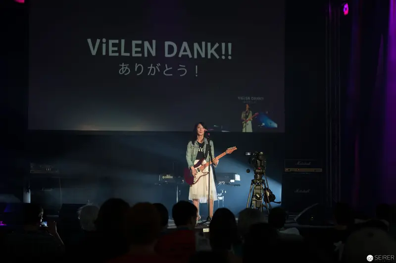 Haruka Performing at AniNite 2018 with Multilingual Gratitude Backdrop