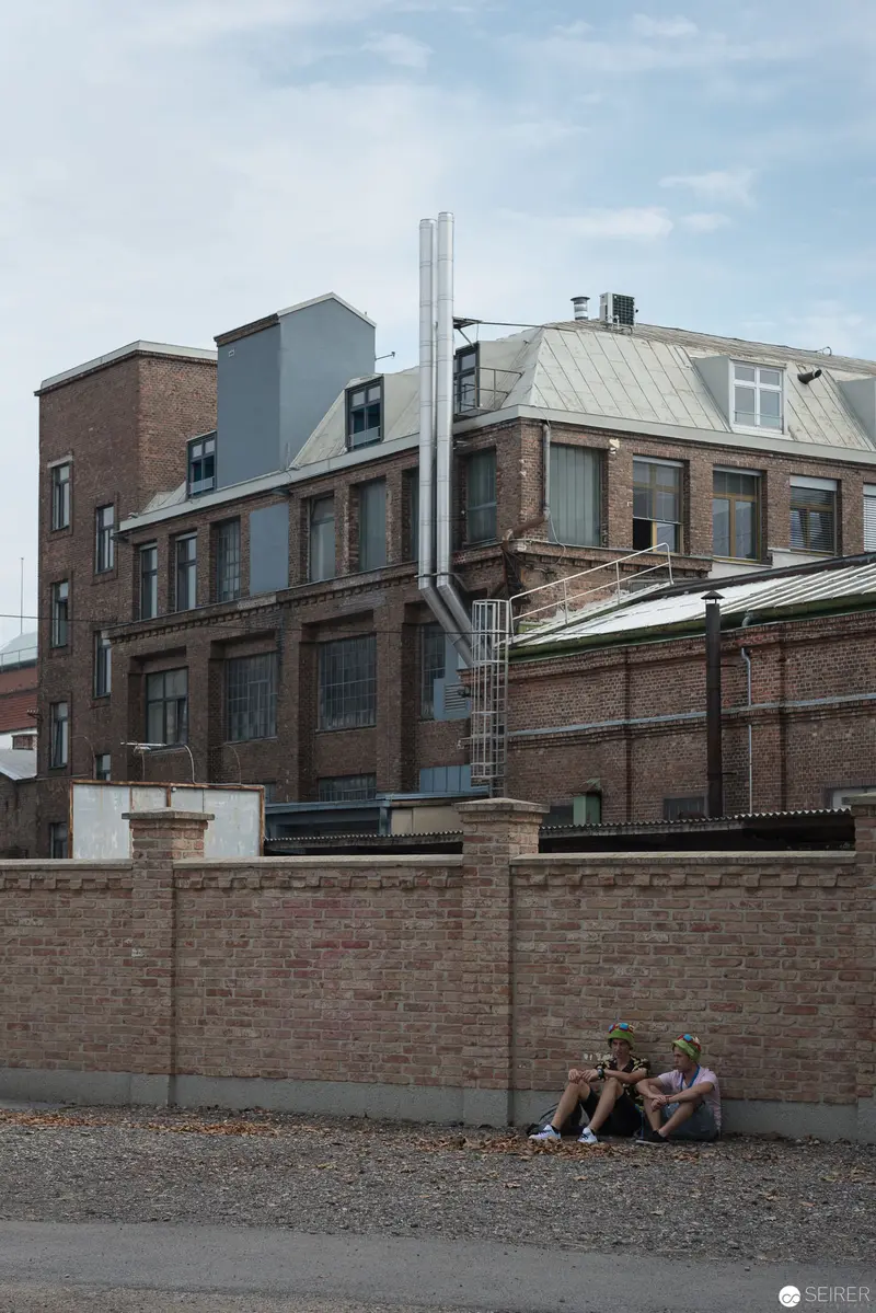 Urban Isolation: Figures Resting Against Industrial Brick Wall Landscape