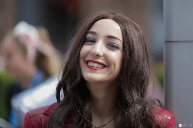 Radiant Smile in Urban Setting: Candid Portrait of Young Woman in Red Leather Jacket