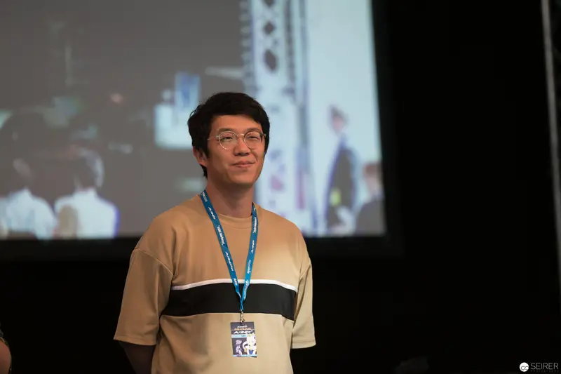 AniNite 2018: Young Presenter in Beige and Black Standing Before Projection Screen