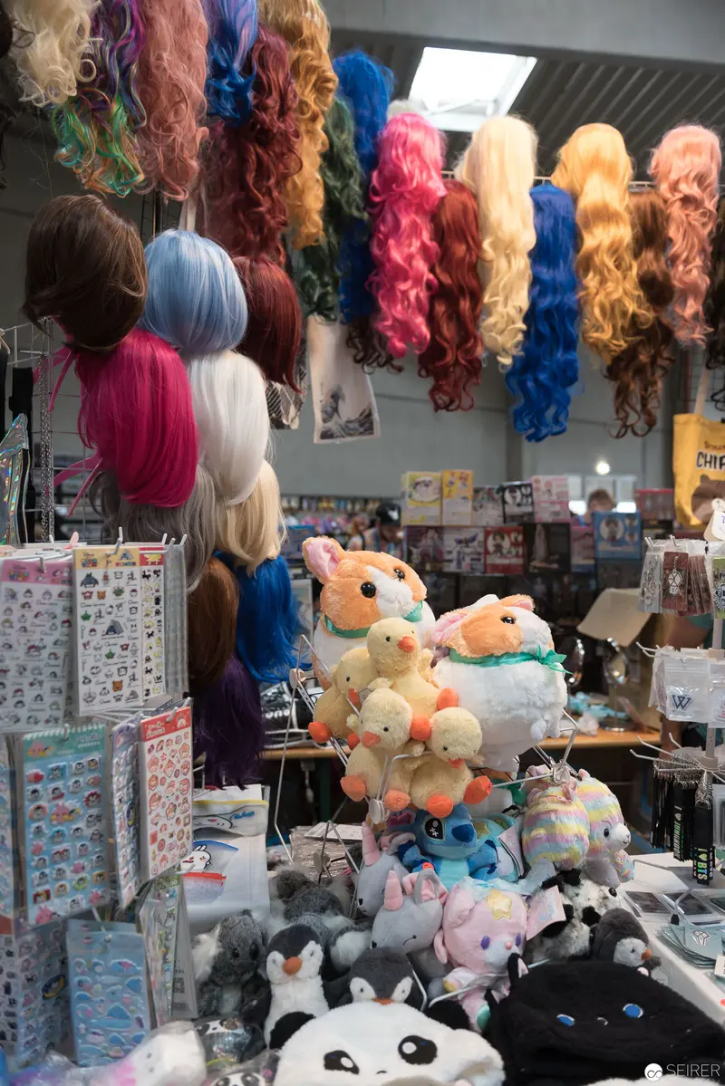 Colorful Cosplay Wigs and Plush Toys at Anime Convention Display