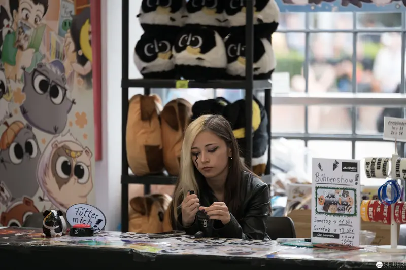 Pensive Young Woman at Merchandise Booth During AniNite 2018 Convention