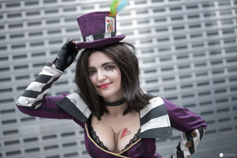 Costumed Performer in Purple Hat and Striped Gloves at Event Backdrop