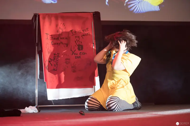 Dramatic Performance at AniNite 2018 with Red Backdrop and Expressive Gesture