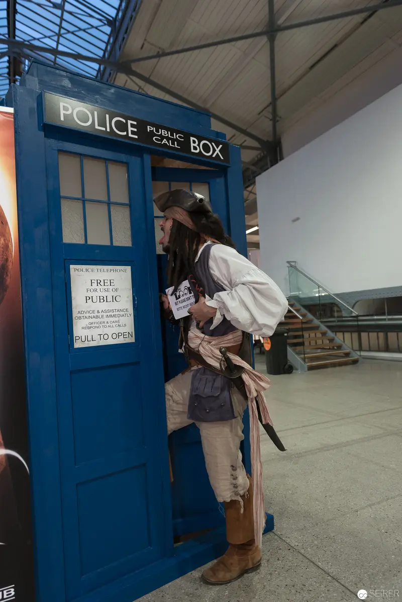 Costumed Individual Examining TARDIS Police Box at Convention