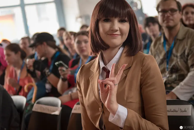 Young Woman in Tan Blazer Gesturing at AniNite 2018 Conference Event
