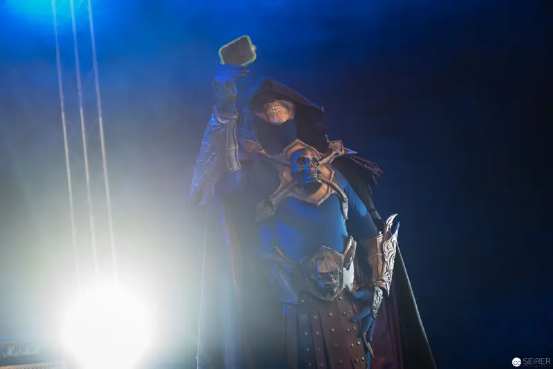 Hooded Performer Wielding Hammer in Dramatic Blue Stage Lighting