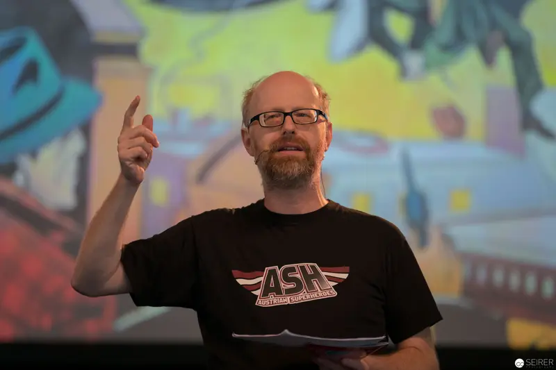 Presenter at AniNite 2018 Gestures During Performance Against Colorful Backdrop