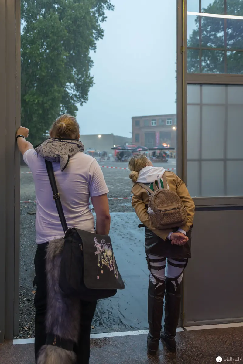 Two Figures Observing Rainy Day Through Window at Unspecified Location