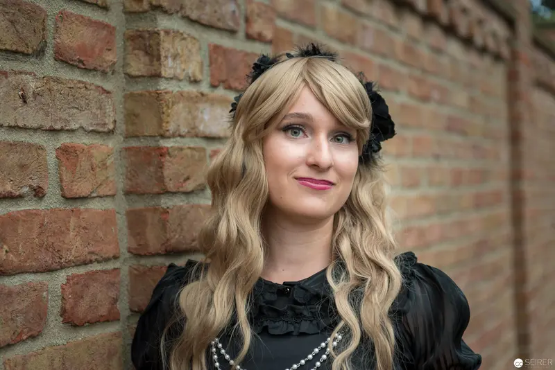 Gothic-Styled Blonde Portrait Against Vintage Brick Wall Backdrop