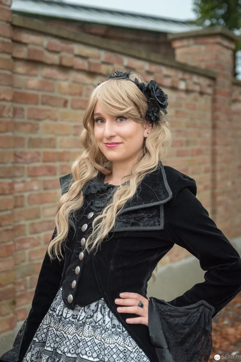 Gothic-Styled Woman in Black Velvet Jacket at Brick Wall Setting