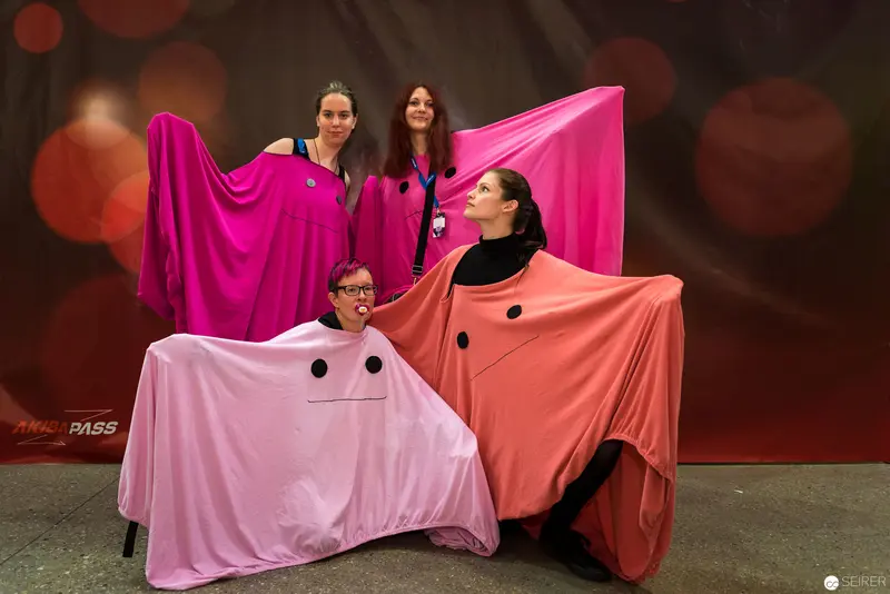 Four Performers in Vibrant Pink and Coral Geometric Draped Costumes