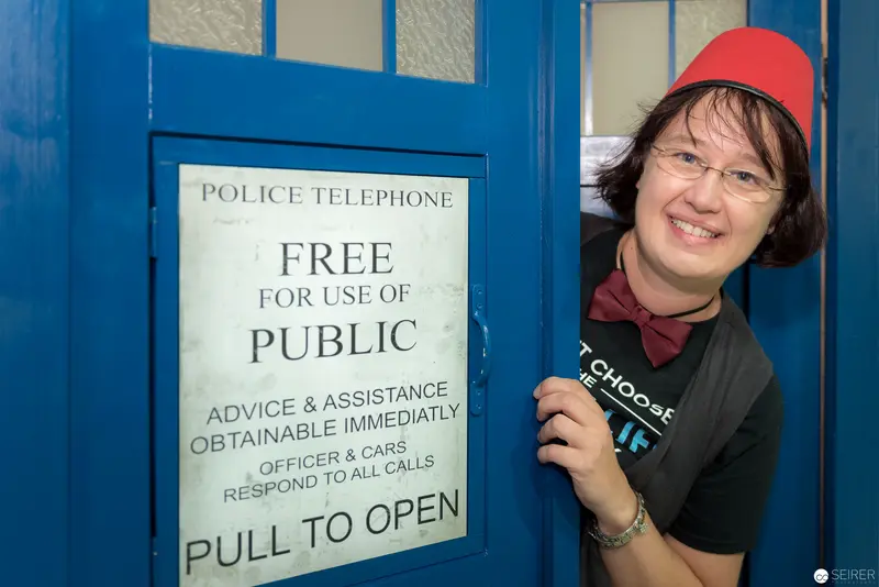 Police Box Entrance with Smiling Person in Red Hat at Public Telephone