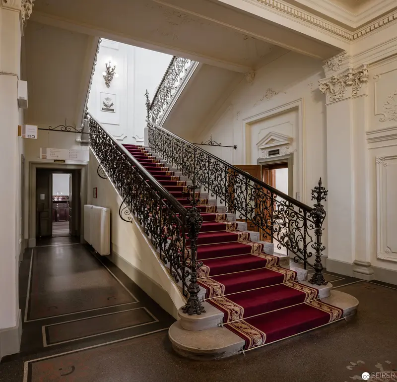 Ornate Interior Staircase with Elaborate Wrought-Iron Railing and Red Carpet Runner