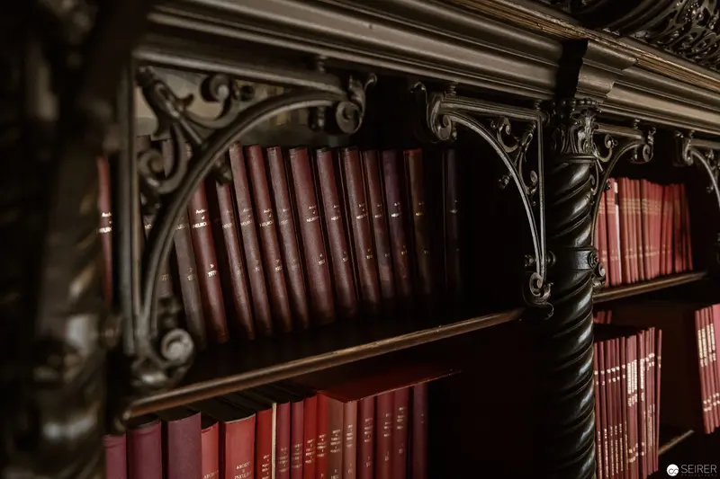 Ornate Victorian Bookshelf with Antique Leather-Bound Volumes in Rich Burgundy Tones