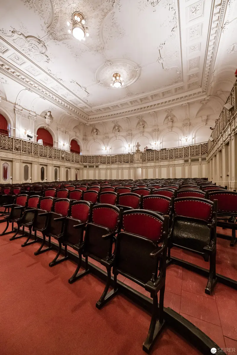 Ornate Auditorium with Red Velvet Chairs and Elaborate Ceiling Decoration
