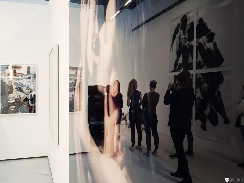 Exhibition View of "Die 90er Jahre" at MUSA Vienna: Gallery Visitors Examining Art