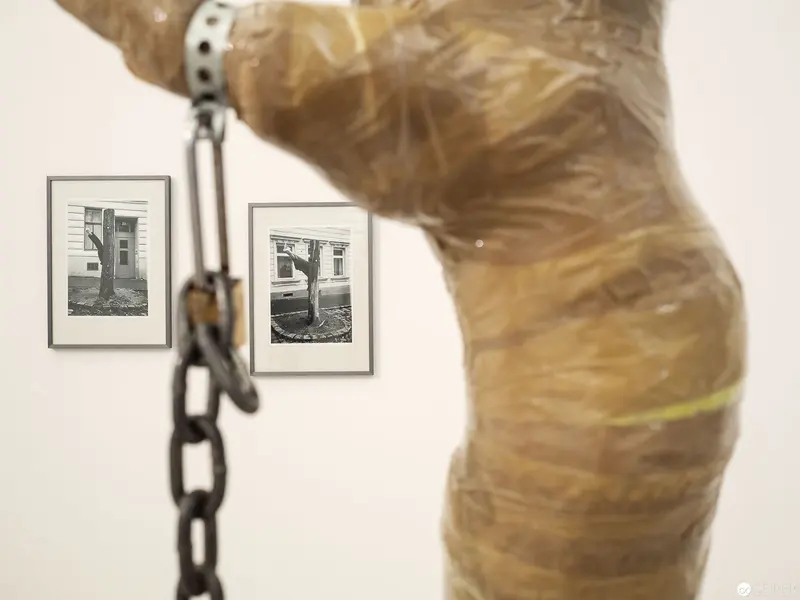 Wrapped Figure with Photographic Diptych and Hanging Chain in Exhibition View