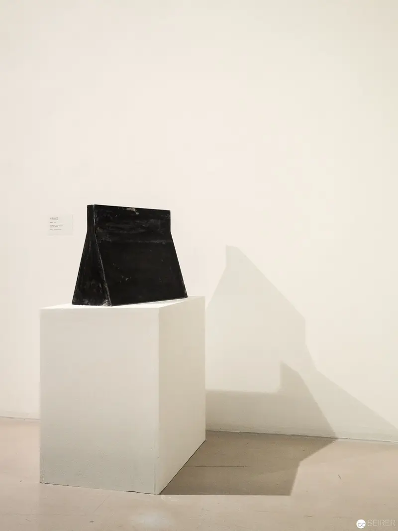 Minimalist Black Sculpture on White Pedestal in Gallery Exhibition Space