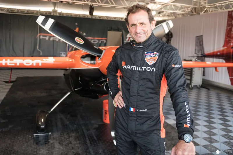 Red Bull Air Race Pilot in Hamilton Racing Suit Beside Aerobatic Aircraft
