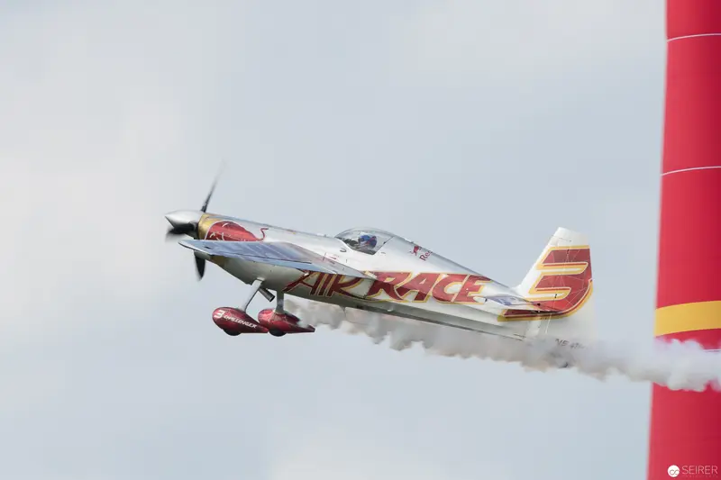 Red Bull Air Race Aerobatic Plane Executing Precision Maneuver Against Gray Sky